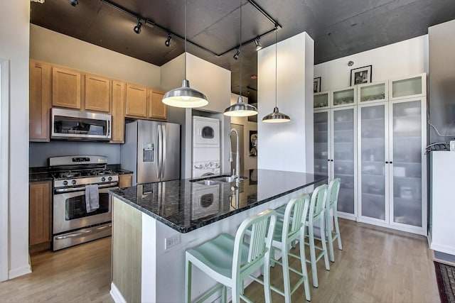 1122 W Catalpa Ave Unit 815, Chicago, IL 60640 - kitchen with stainless steel appliances, track lighting, stacked washer / drying machine, light wood finished floors, and dark stone countertops