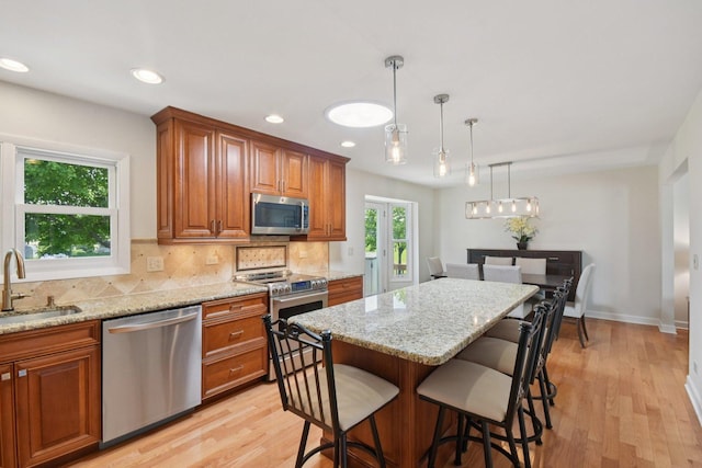 5085 Dukesberry Ln, Hoffman Estates, IL 60010 - kitchen featuring stainless steel appliances, brown cabinets, a breakfast bar area, light stone countertops, and recessed lighting