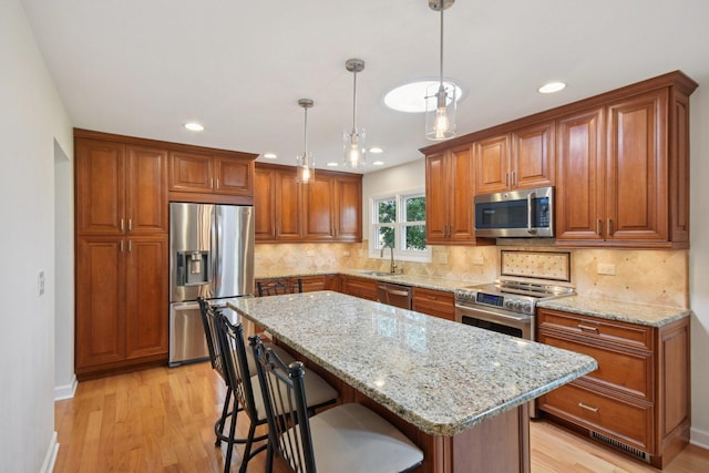 5085 Dukesberry Ln, Hoffman Estates, IL 60010 - kitchen featuring stainless steel appliances, brown cabinets, recessed lighting, light wood-style floors, and light stone countertops
