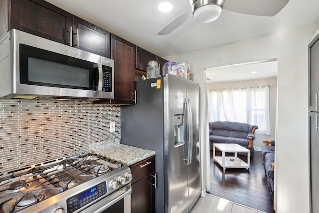2023 Kristan Ave, North Chicago, IL 60064 - kitchen with appliances with stainless steel finishes, a ceiling fan, dark brown cabinetry, tasteful backsplash, and light stone countertops