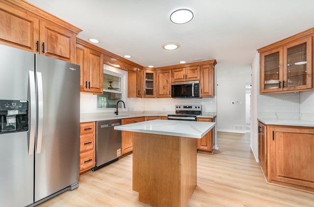 208 Webster Ln, Schaumburg, IL 60193 - kitchen with appliances with stainless steel finishes, light wood-type flooring, decorative backsplash, a center island, and brown cabinetry