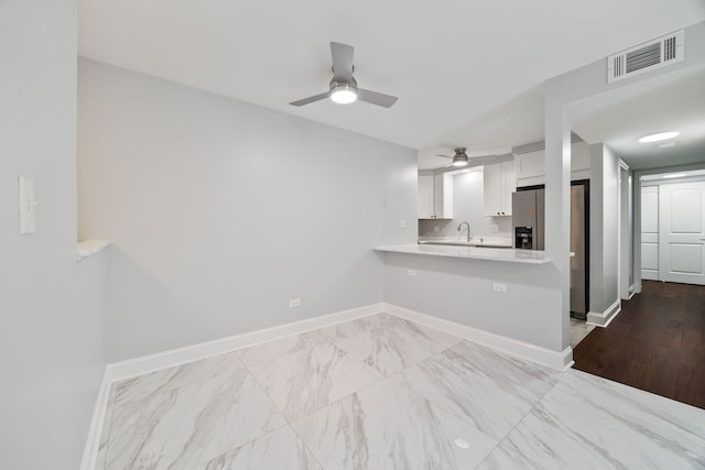 8232 Niles Center Rd Unit 101, Skokie, IL 60077 - kitchen with light countertops, white cabinets, a peninsula, ceiling fan, and marble finish flooring