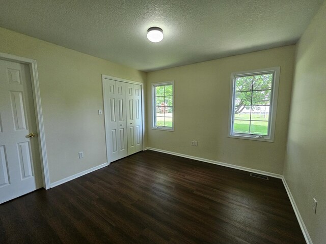 210 Barrington Dr, Bourbonnais, IL 60914 - unfurnished bedroom with dark wood-style floors, a textured ceiling, and a closet