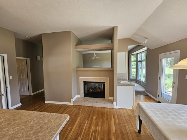 210 Barrington Dr, Bourbonnais, IL 60914 - unfurnished living room with wood finished floors, a ceiling fan, a fireplace with raised hearth, vaulted ceiling, and a textured ceiling