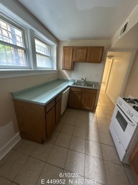 947 E Hyde Park Blvd Unit G, Chicago, IL 60615 - kitchen with white appliances, light tile patterned floors, light countertops, and brown cabinetry