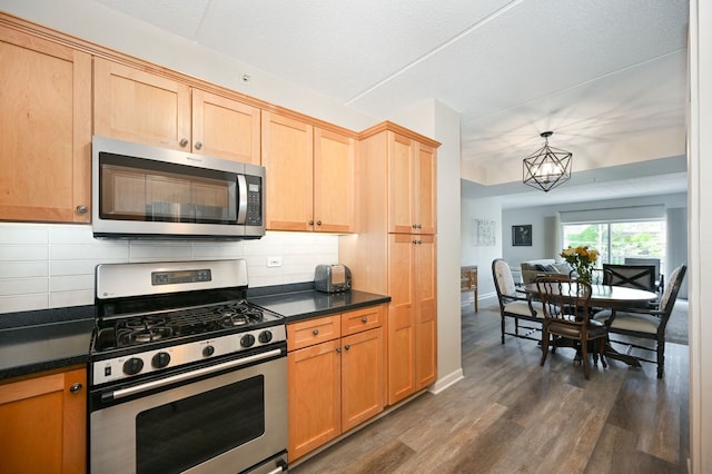 570 Crescent Blvd Unit 307, Glen Ellyn, IL 60137 - kitchen featuring appliances with stainless steel finishes, dark countertops, dark wood finished floors, and tasteful backsplash
