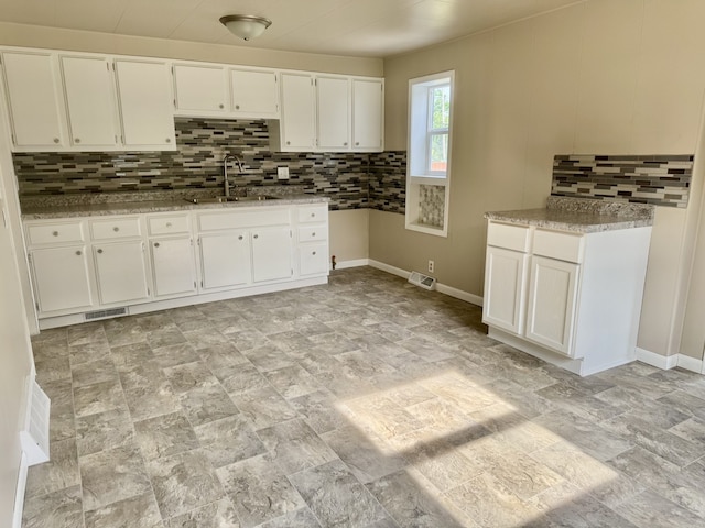 401 E 1st St, Oglesby, IL 61348 - kitchen with decorative backsplash, white cabinetry, light stone countertops, and stone finish floors