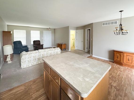 645 Tally St, Earlville, IL 60518 - kitchen with a chandelier, open floor plan, a center island, light countertops, and wood finished floors