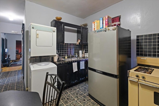 5440 S Paulina St, Chicago, IL 60609 - kitchen featuring freestanding refrigerator, estacked washer and dryer, white range with gas cooktop, and tasteful backsplash