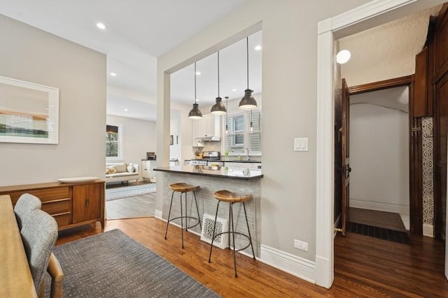 3739 W Palmer St, Chicago, IL 60647 - kitchen with wood finished floors, a kitchen bar, stainless steel range, recessed lighting, and under cabinet range hood
