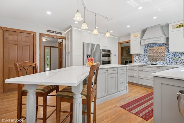 42 N Holly Ave, Fox Lake, IL 60020 - kitchen featuring custom range hood, appliances with stainless steel finishes, a center island, decorative backsplash, and decorative light fixtures
