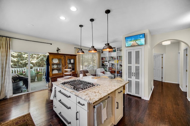 361 Cascade Ln Unit 1, Oswego, IL 60543 - kitchen featuring stainless steel gas stovetop, arched walkways, dark wood finished floors, hanging light fixtures, and light stone countertops