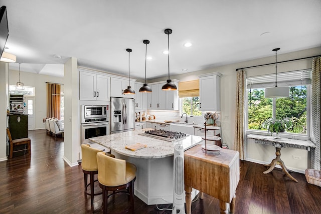 361 Cascade Ln Unit 1, Oswego, IL 60543 - kitchen with stainless steel appliances, a center island, light stone counters, dark wood-type flooring, and recessed lighting
