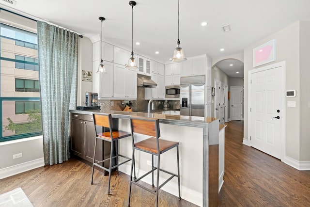 841 W Monroe St Unit 4A, Chicago, IL 60607 - kitchen with built in appliances, arched walkways, a peninsula, wood finished floors, and under cabinet range hood