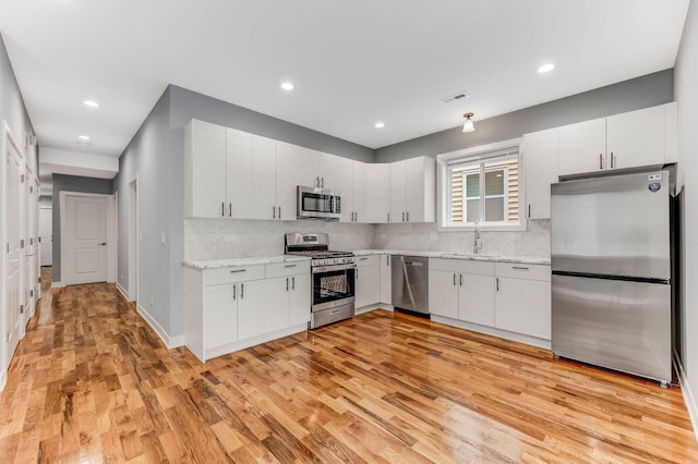 2708 W Jackson Blvd, Chicago, IL 60612 - kitchen with appliances with stainless steel finishes, light wood-style floors, decorative backsplash, recessed lighting, and white cabinets