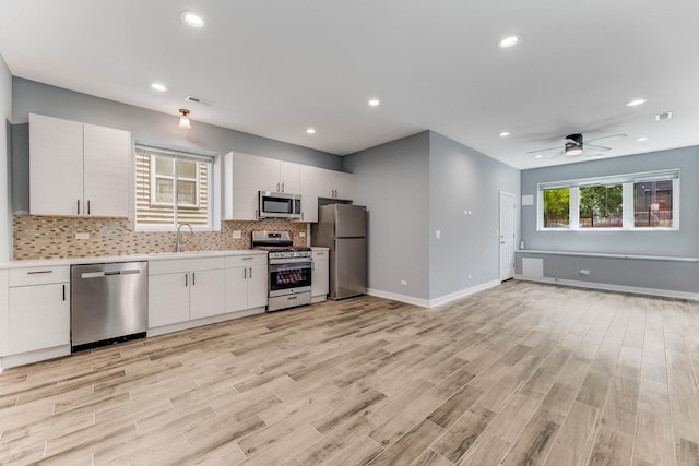 2708 W Jackson Blvd, Chicago, IL 60612 - kitchen with appliances with stainless steel finishes, light countertops, light wood-type flooring, decorative backsplash, and white cabinetry