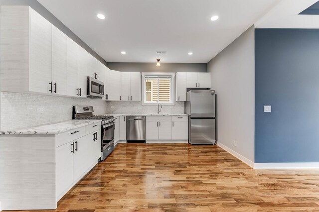 2708 W Jackson Blvd, Chicago, IL 60612 - kitchen with appliances with stainless steel finishes, tasteful backsplash, light wood-style flooring, light stone countertops, and white cabinets