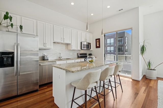 1719 N Western Ave Unit 4, Chicago, IL 60647 - kitchen with appliances with stainless steel finishes, wood finished floors, a kitchen breakfast bar, a kitchen island, and recessed lighting