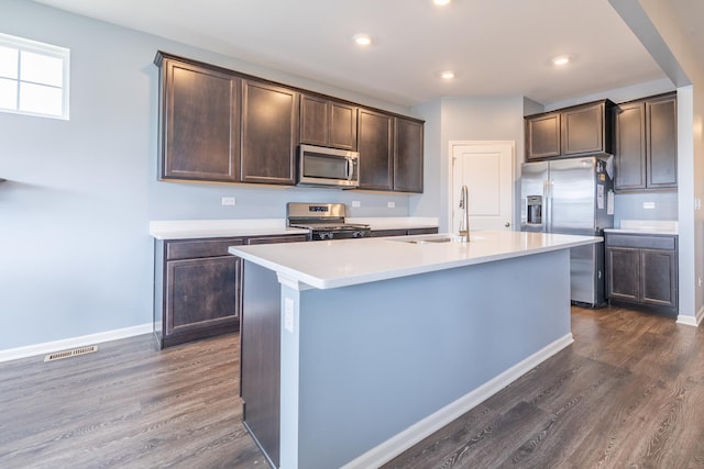 738 Kentshire Cir, Elgin, IL 60124 - kitchen featuring appliances with stainless steel finishes, dark brown cabinets, dark wood-type flooring, light countertops, and a kitchen island with sink