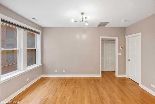 2305 N Kimball Ave Unit 1, Chicago, IL 60647 - empty room with light wood-style floors, a chandelier, and a smoke detector