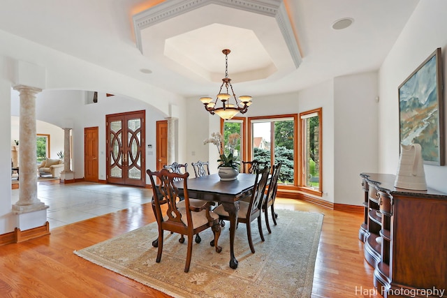 39 Forest Ln, South Barrington, IL 60010 - dining room with decorative columns, a chandelier, arched walkways, a tray ceiling, and light wood-type flooring