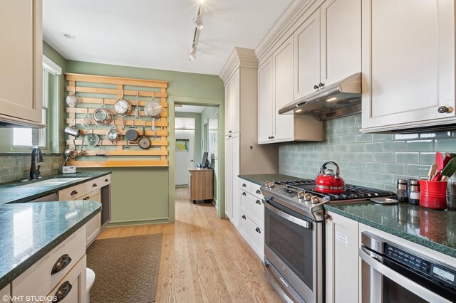 2440 N Lakeview Ave Unit 14E, Chicago, IL 60614 - kitchen featuring appliances with stainless steel finishes, under cabinet range hood, light wood-style floors, backsplash, and white cabinetry