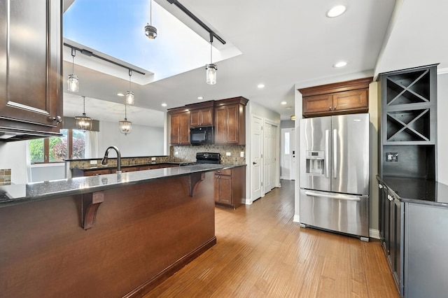 12449 W Prairie Dr, Homer Glen, IL 60491 - kitchen featuring stainless steel refrigerator with ice dispenser, black microwave, light wood finished floors, a kitchen breakfast bar, and stove