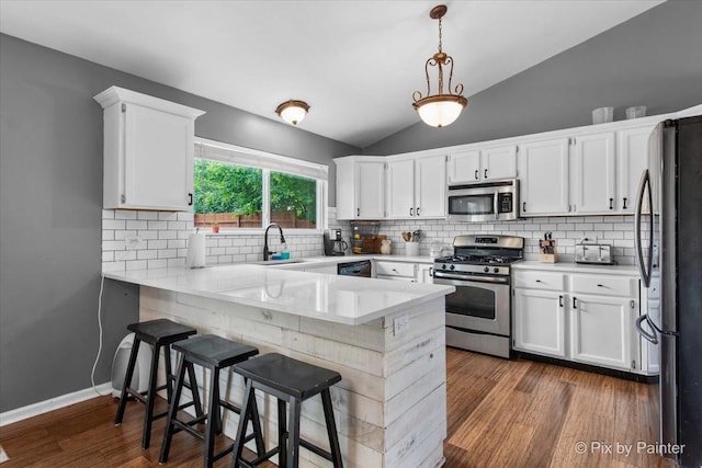 903 Pin Oak Cir, Cary, IL 60013 - kitchen with appliances with stainless steel finishes, a peninsula, vaulted ceiling, dark wood-style floors, and white cabinets