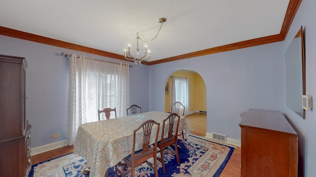 3354 N Overhill Ave, Chicago, IL 60634 - dining space with arched walkways, a chandelier, ornamental molding, and light wood-type flooring