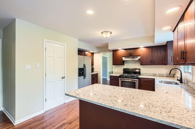 918 Carol Ln, Crete, IL 60417 - kitchen with gas range, white fridge with ice dispenser, under cabinet range hood, a peninsula, and wood finished floors