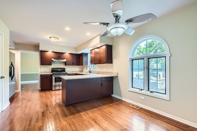 918 Carol Ln, Crete, IL 60417 - kitchen featuring stainless steel range with gas cooktop, under cabinet range hood, fridge with ice dispenser, dark brown cabinetry, and a peninsula