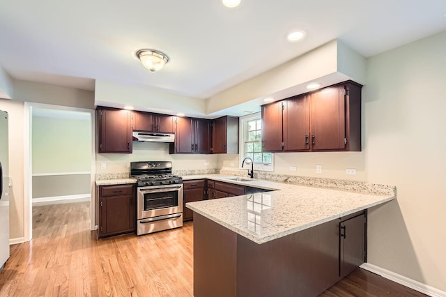 918 Carol Ln, Crete, IL 60417 - kitchen featuring stainless steel gas range, under cabinet range hood, a peninsula, light wood finished floors, and light stone counters