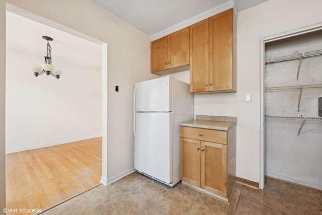 2424 W Farragut Ave Unit 3B, Chicago, IL 60625 - kitchen featuring freestanding refrigerator, light countertops, a chandelier, decorative light fixtures, and brown cabinetry