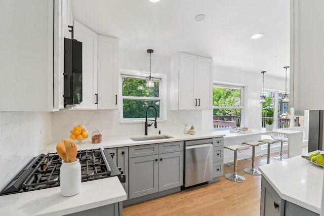 7248 N Kildare Ave, Lincolnwood, IL 60712 - kitchen with stainless steel dishwasher, backsplash, decorative light fixtures, gray cabinets, and light wood-type flooring
