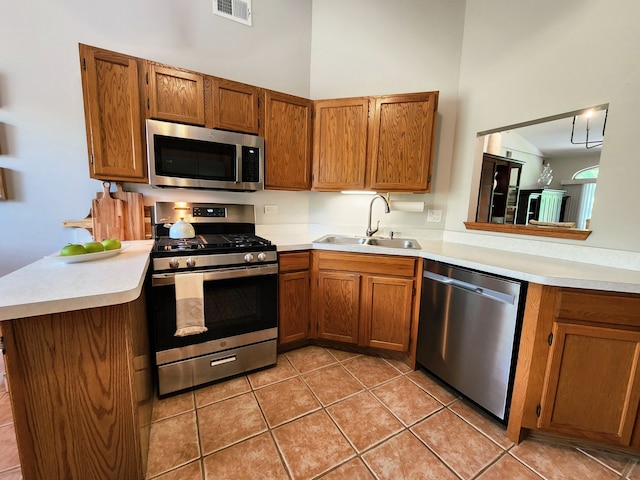 9410 S 77th Ct Unit 3F, Hickory Hills, IL 60457 - kitchen with stainless steel appliances, a peninsula, brown cabinetry, light countertops, and light tile patterned floors
