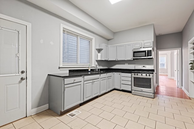 2713 W 24th Pl, Chicago, IL 60608 - kitchen with stainless steel appliances, dark countertops, light tile patterned floors, and open shelves