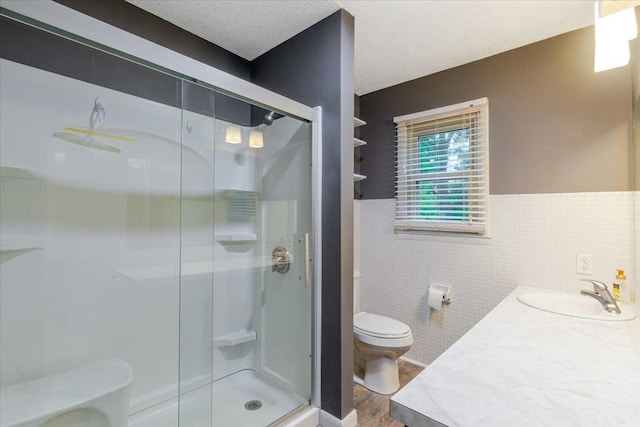 106 Sandra Ln, Normal, IL 61761 - bathroom with tile walls, a shower stall, wood finished floors, vanity, and wainscoting