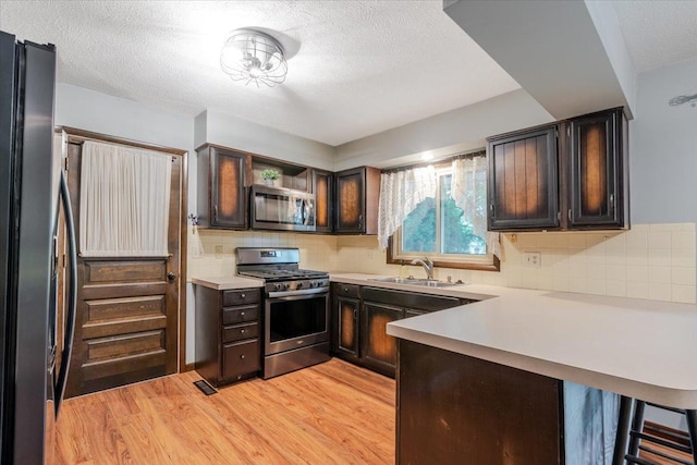 106 Sandra Ln, Normal, IL 61761 - kitchen featuring stainless steel appliances, a peninsula, a textured ceiling, light countertops, and light wood-type flooring