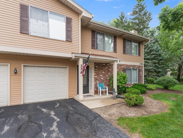 33 E Hickory St Unit A, Lombard, IL 60148 - view of property featuring brick siding, an attached garage, a chimney, and asphalt driveway