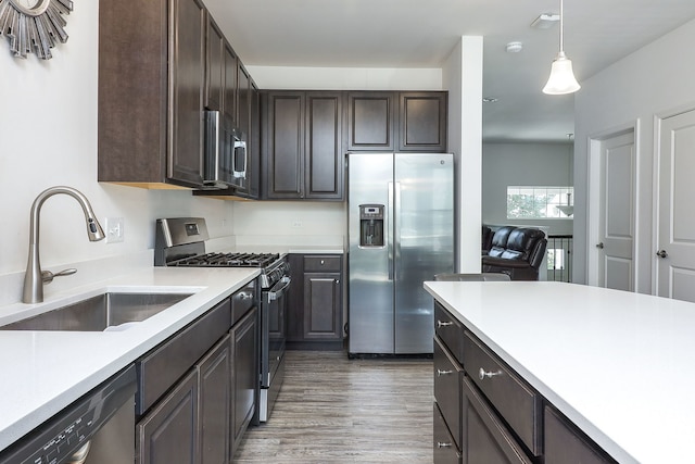 277 Lakeshore Dr, Oswego, IL 60543 - kitchen featuring appliances with stainless steel finishes, dark brown cabinets, light countertops, light wood-style floors, and hanging light fixtures