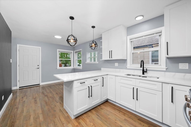7133 S Honore St, Chicago, IL 60636 - kitchen featuring a peninsula, light countertops, white cabinets, light wood-style floors, and decorative light fixtures