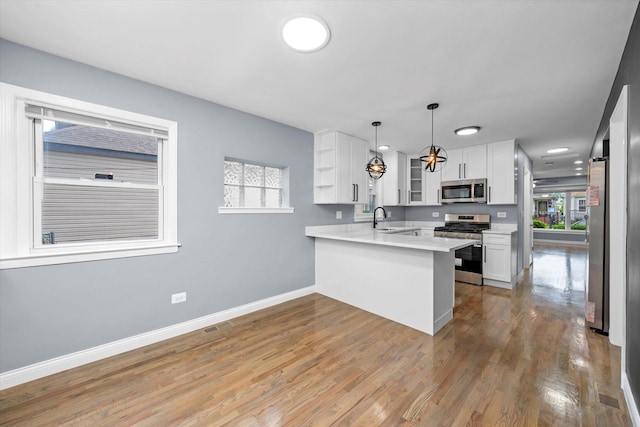 7133 S Honore St, Chicago, IL 60636 - kitchen featuring stainless steel appliances, a peninsula, white cabinetry, glass insert cabinets, and light wood-style floors
