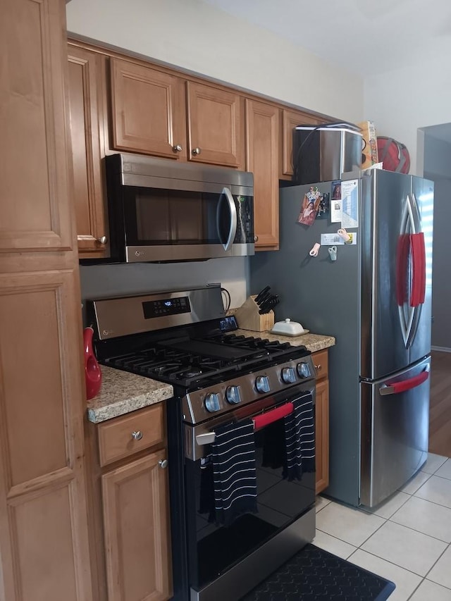 853 Greenbriar Ln, University Park, IL 60484 - kitchen with stainless steel appliances, light tile patterned floors, brown cabinets, and light stone counters