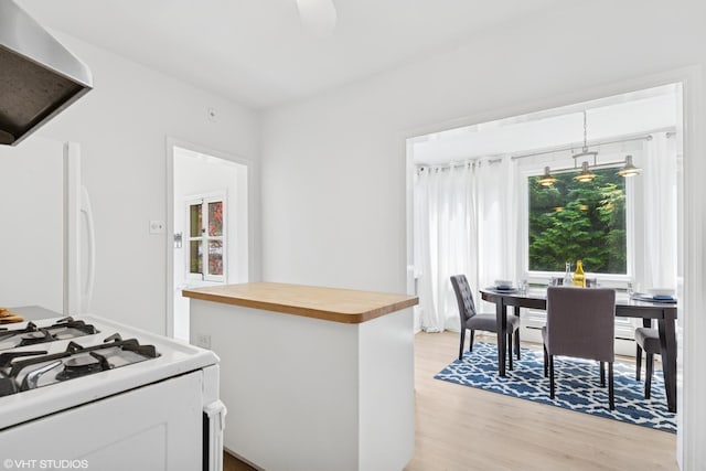 2635 Poplar Ave, Evanston, IL 60201 - kitchen with butcher block countertops, range hood, white appliances, light wood-type flooring, and hanging light fixtures