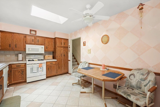 9242 Pembrooke Ln, Orland Park, IL 60462 - kitchen featuring white appliances, brown cabinets, a skylight, light countertops, and wallpapered walls