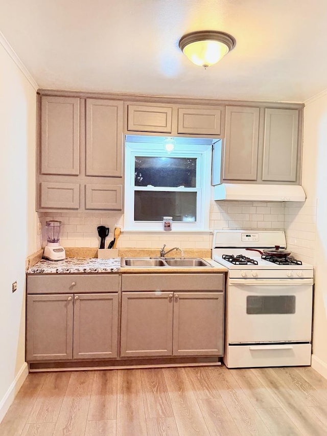 1318 Pine Grove Ave, Round Lake Beach, IL 60073 - kitchen with white range with gas cooktop, under cabinet range hood, backsplash, light countertops, and crown molding