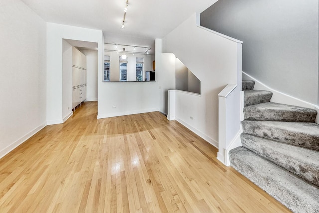 1223 W Cottage Pl, Chicago, IL 60607 - unfurnished living room with hardwood / wood-style flooring, track lighting, and stairs
