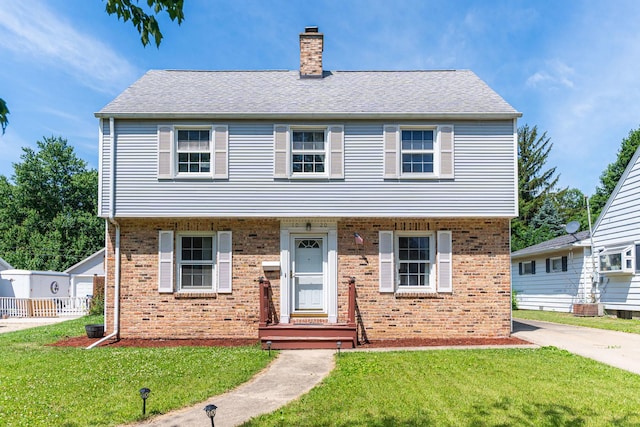 1020 N 8th St, Rochelle, IL 61068 - colonial inspired home with a chimney, brick siding, a front yard, and a shingled roof