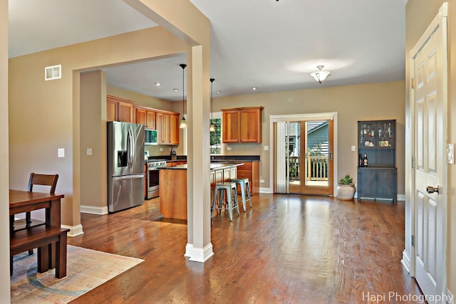 1340 Park Ave, Winthrop Harbor, IL 60096 - kitchen with appliances with stainless steel finishes, dark countertops, brown cabinetry, dark wood-type flooring, and a breakfast bar