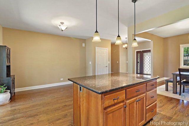 1340 Park Ave, Winthrop Harbor, IL 60096 - kitchen with dark wood-style flooring, pendant lighting, a kitchen island, dark stone counters, and brown cabinetry